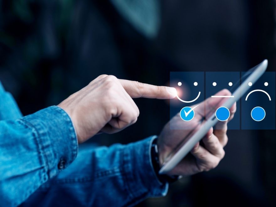 Person wählt Smiley auf Tablet aus.
